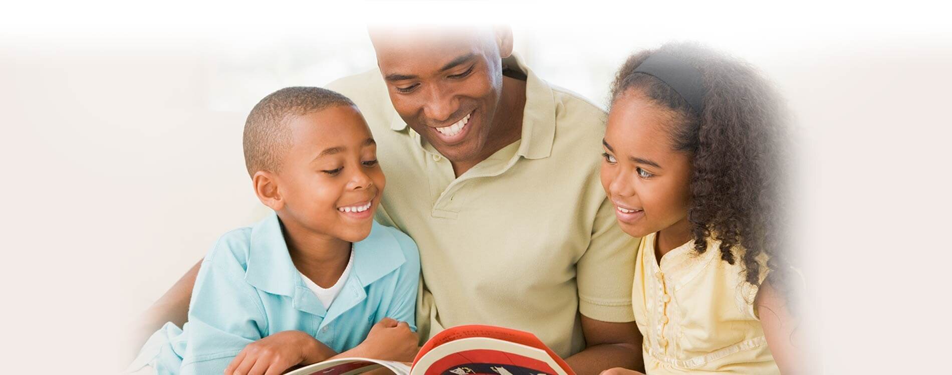 A father and his 2 children reading a book.