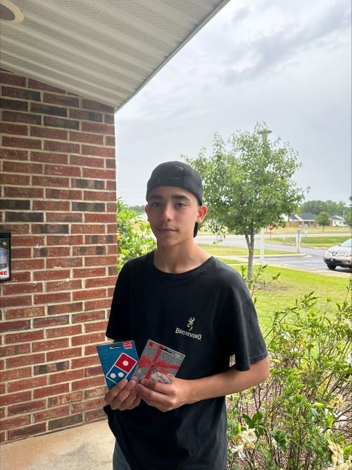 A boy holding two gift cards.