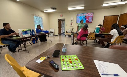 Seven people sitting and playing Bingo.