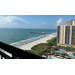 View of the ocean, beach, and hotel from a balcony.