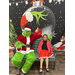Young girl in a dress sitting next to the Grinch.
