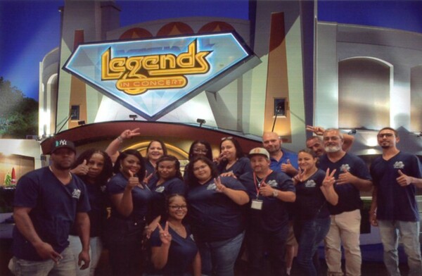 A group of people standing together and smiling together for a picture. 